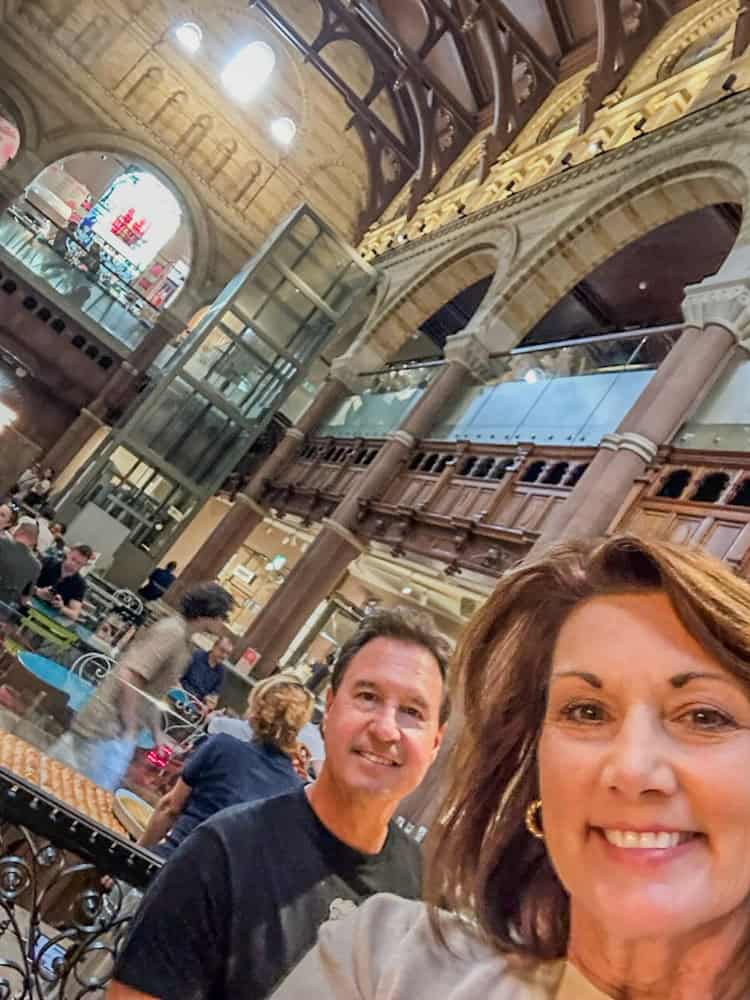 Elegant interior of a historic building with ornate architecture and a lively crowd enjoying their visit.